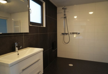 Bagno moderno in un lodge con doccia a filo pavimento, piastrelle bicolore e lavabo bianco.