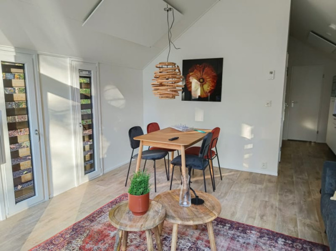 Interior luminoso de lodge con mesa de comedor, cuatro sillas, alfombra colorida y decoración moderna.