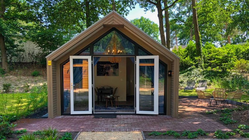 Foto einer gemütlichen Lodge mit offenen Türen, mitten im Grünen und von Bäumen umgeben.