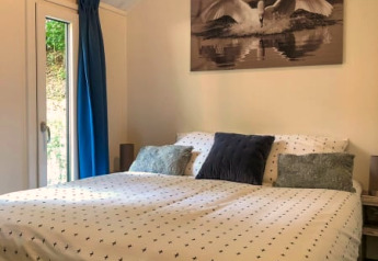 Camera accogliente in un lodge con letto grande, tende blu e quadro di un cigno sopra il letto.