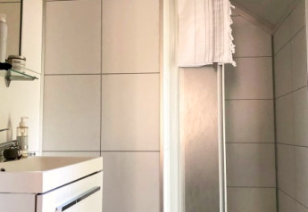 Bagno moderno in un lodge, piastrelle bianche, lavabo, specchio e box doccia con asciugamano.