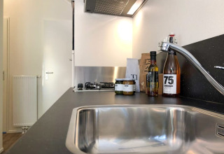 Cucina moderna in un lodge con lavello in acciaio, rubinetto, piano di lavoro, bottiglie e vasetti di cibo.