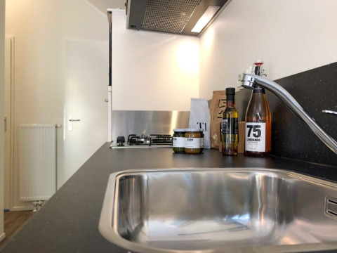 Cucina moderna in un lodge con lavello in acciaio, rubinetto, piano di lavoro, bottiglie e vasetti di cibo.