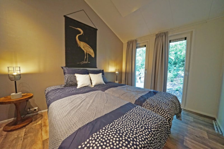 Gemütliches Schlafzimmer in einer Lodge mit Doppelbett, Naturblick und moderner Dekoration.