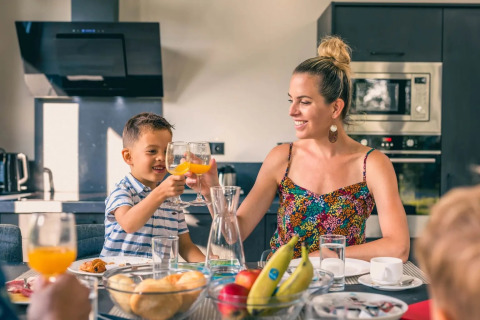 Moeder en zoon genieten samen van een gezellig ontbijt in een moderne keuken van een vakantiepark glamping.
