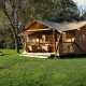 Glamping-telt La Vida ved Resort de Parel i Holland, omgivet af grønt græs og træer, på en solrig dag.