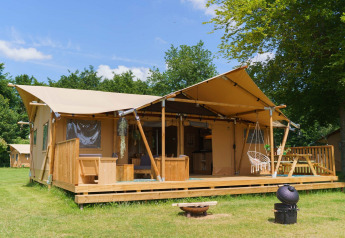Tenda glamping La Gran Vida al Resort de Parel nei Paesi Bassi, con veranda in legno e sedia sospesa.