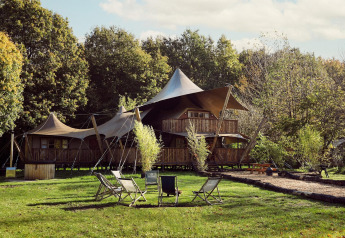 Luxuriöses Safarizelt Hacienda beim Resort de Parel in den Niederlanden, umgeben von Wald und Sitzstühlen.