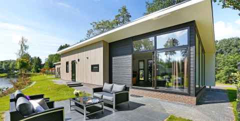 Lodge Grand Modern bij Holiday Park De Lochemse Berg in Nederland met grote ramen, tuin en modern terras.