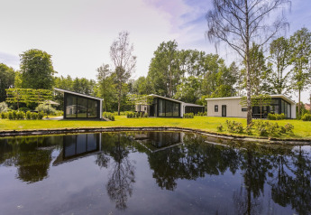 Moderne lodges in Holiday Park De Lochemse Berg in Nederland, naast een vijver en omringd door natuur.