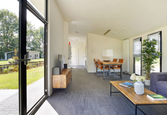 Moderne lodge woonkamer met grote ramen en tuinzicht in Holiday Park De Lochemse Berg, Nederland.