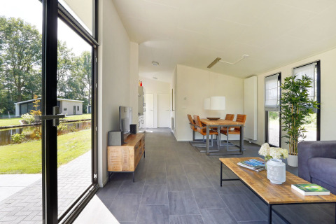 Moderne lodge stue med store vinduer og udsigt til haven i Holiday Park De Lochemse Berg, Holland.