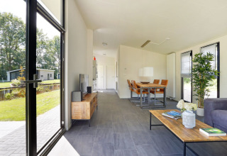 Sala de estar de lodge moderno con grandes ventanas y vista al jardín en Holiday Park De Lochemse Berg, Países Bajos.