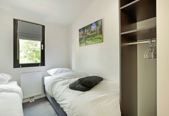 Habitación con dos camas individuales, ventana, armario abierto y cuadro en Lodge Grand Modern, De Lochemse Berg.