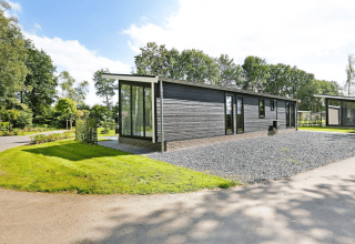 Lodge Grand Modern op vakantiepark De Lochemse Berg in Nederland, omgeven door groen en bomen.