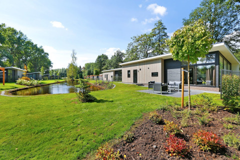 Moderne Lodge Grand met terras en grote ramen aan vijver in Vakantiepark De Lochemse Berg, Nederland.
