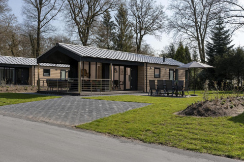 Moderne Lodge im Holiday Park De Lochemse Berg in den Niederlanden mit Terrasse und Gartenmöbeln.