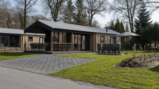 Moderne lodge in Holiday Park De Lochemse Berg in Nederland, met terras, tuinset en een groene buitenruimte.