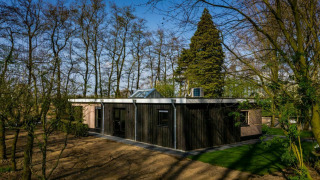 Casa moderna Nature House en Buitengoed Ruysbos, Países Bajos, rodeada de naturaleza y árboles primaverales.