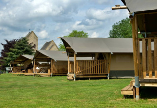 Tiendas safari en Camping La Dolce Vita, Países Bajos, con terrazas de madera y césped verde bajo el cielo.