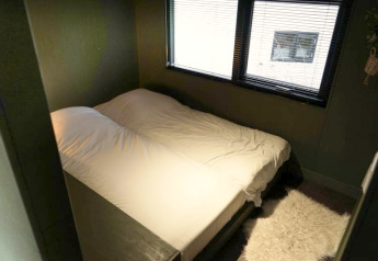 Hébergement glamping confortable avec lit double, draps blancs, tapis moelleux et fenêtres à stores.