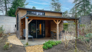 Hébergement de glamping confortable avec terrasse couverte en bois et coin salon extérieur, au cœur de la nature.