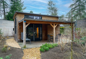 Hébergement de glamping confortable avec terrasse couverte en bois et coin salon extérieur, au cœur de la nature.