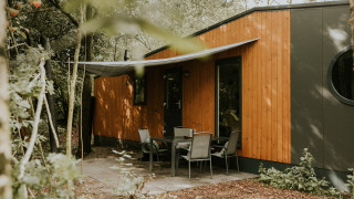 Vista exterior de Happy Bee Lodge con revestimiento de madera y patio, Camping Si-Es-An en los Países Bajos.