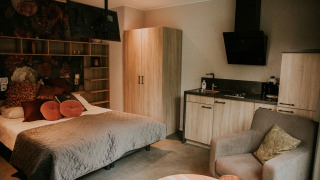 Interior de casa tiny Luxury loft en Camping Si-Es-An, Países Bajos, con cama, cocina y sillón cómodo.