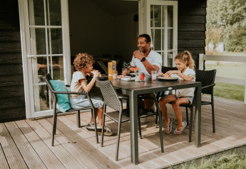 Famiglia che si gode un pasto all'aperto sulla terrazza del Forest lodge, Camping Si-Es-An nei Paesi Bassi.