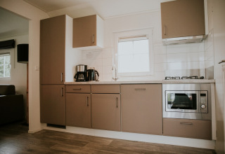 Moderne keuken in Forest Lodge bij Camping Si-Es-An in Nederland met oven, fornuis en koffiezetapparaat.