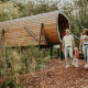 Familie, der nyder naturen foran en Skycabin på Camping Si-Es-An i Nederlandene omgiven af træer.