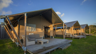 Comfort Safari tent al Camping 't Veld nei Paesi Bassi, con veranda in legno e arredo da esterno.