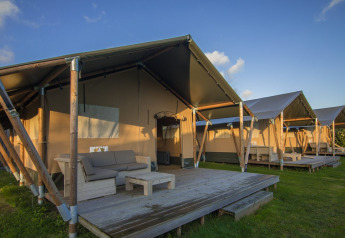Tiendas safari Comfort en Camping 't Veld, Países Bajos, con porches y muebles de exterior de madera.