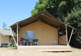 Safaritent met badkamer bij Rhederlaagse Meren, Nederland, met veranda en tuinmeubilair vooraan.