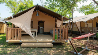 Vista del lodge Villatent Outback en Camping Au Clos de La Chaume, Francia, con terraza y hamaca exterior.