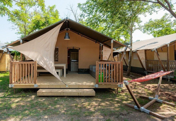 Vista del lodge Villatent Outback en Camping Au Clos de La Chaume, Francia, con terraza y hamaca exterior.