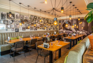 Restaurant moderne avec un mur de photos en noir et blanc, des lumières suspendues et des sièges confortables.