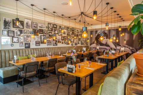 Modern restaurant met een fotomuur in zwart-wit, warme verlichting en comfortabele zitplaatsen.