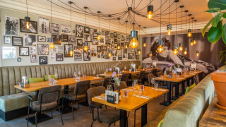 Restaurante moderno con pared decorada con fotos en blanco y negro, luces cálidas y asientos confortables.