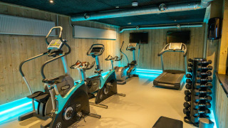 Gimnasio moderno en un parque vacacional de glamping con caminadoras, bicicletas y pesas disponibles.