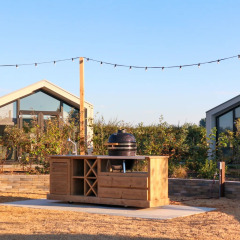 Cabañas modernas de glamping, cocina exterior y luces en un parque vacacional al aire libre y soleado.