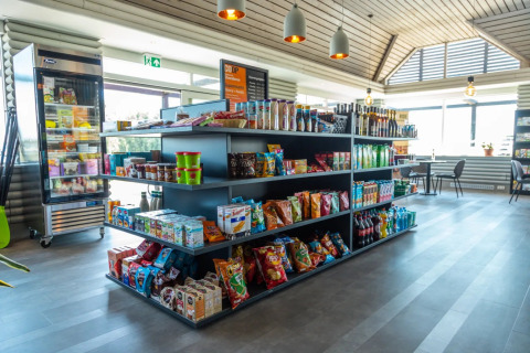 Tienda moderna en parque vacacional con glamping, variedad de snacks, bebidas y áreas para sentarse.
