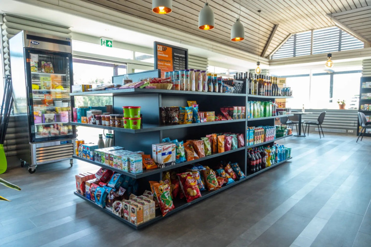 Modern shop in a holiday park with glamping, offering a variety of snacks, drinks, and seating.
