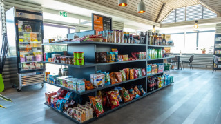 Tienda moderna en parque vacacional con glamping, variedad de snacks, bebidas y áreas para sentarse.