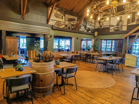 Acogedor restaurante con decoración de madera, barril de vino y fotos murales en un parque de glamping.
