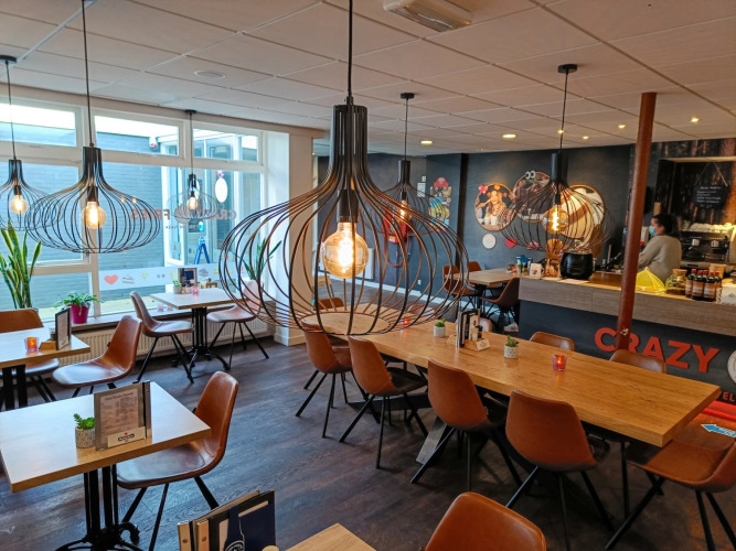 Gemütliches Café in einem Ferienpark mit stilvollen Lampen und Sitzbereichen, ideal für Glamping-Gäste.