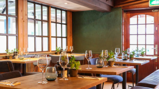 Gezellig restaurant met houten tafels en planten in een vakantiepark dat glamping accommodaties biedt.