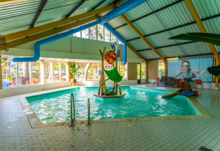 Overdekt zwembad met kindvriendelijke speelelementen in een vakantiepark met glampingaccommodaties in de natuur.