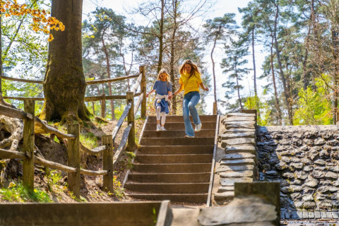 Eine Frau und ein Kind laufen eine Treppe im Wald hinunter, in einem Ferienpark mit Glamping.